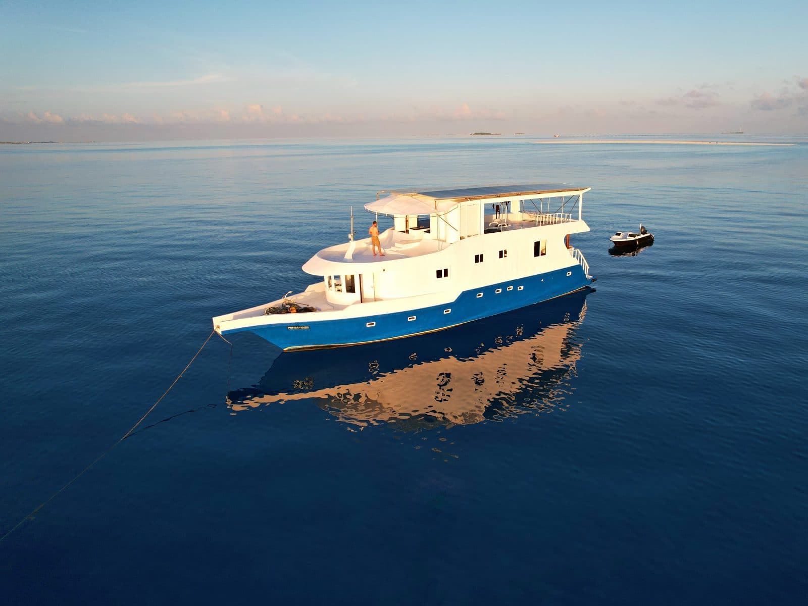 The NOAH safari boat at anchor on glassy water in early-morning golden light